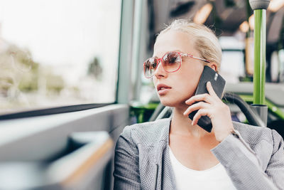 Portrait of young woman wearing sunglasses while sitting in car