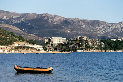 Sailboat on sea by buildings in city against sky