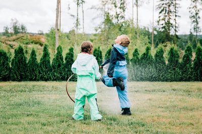 Brother and sister spraying each other with water in the yard at home