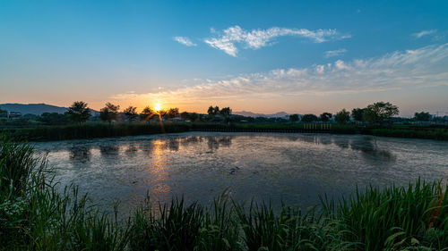 Scenic view of lake against sky at sunset