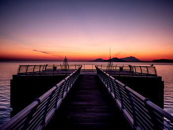 Pier over sea against sky during sunset