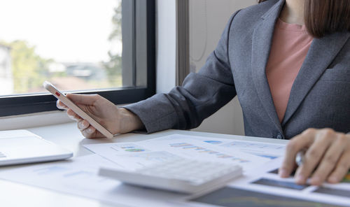 Midsection of woman using smart phone on table