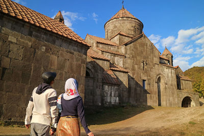 Rear view of couple standing by historical building against sky