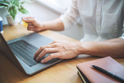 Midsection of man using laptop on table