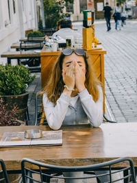 Girl with head in hands sitting at cafe