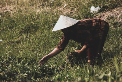 Mature woman wearing hat while working on farmland 