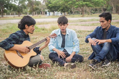 Man playing guitar while sitting at park