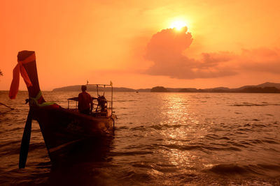 Longtail boat moving on sea against sky during sunset