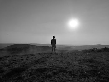 Rear view of man standing at beach against sky