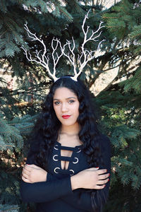 Portrait of young woman standing against trees