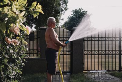 Man holding umbrella standing in yard