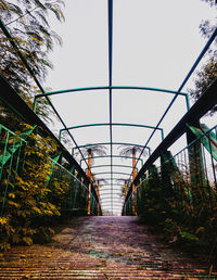 Footbridge amidst trees against clear sky