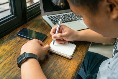 Man writing in notepad at table