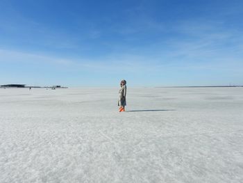 Rear view of woman walking on beach against sky