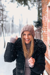 Portrait of smiling young woman standing outdoors during winter