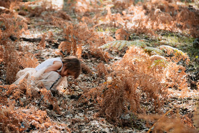 Side view of girl crouching amidst plants on field