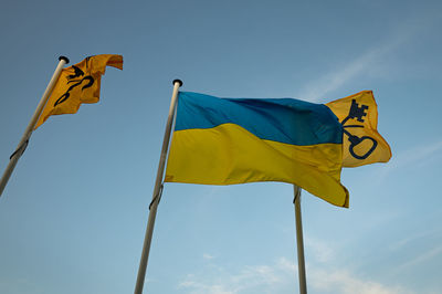 Flying blue yellow flag of ukraine near dutch town hall. symbol to support the ukrainians in the war