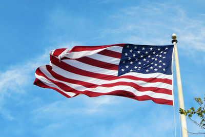 Low angle view of american flag against blue sky