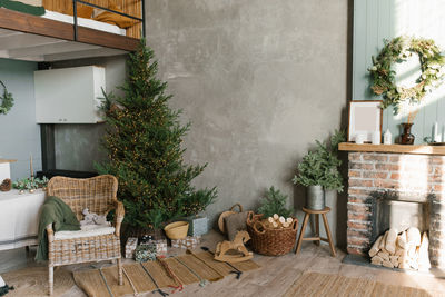 The interior of a country house with a fireplace, a christmas tree, a wicker chair and decor 