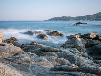 Rocks in sea against clear sky