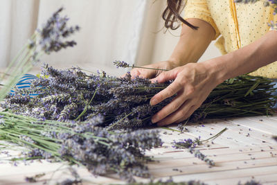 Midsection of florist arranging bunch of lavender flowers on table