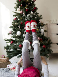 Low section of girl with feet on christmas tree