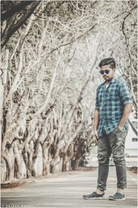 Full length portrait of young man standing against trees