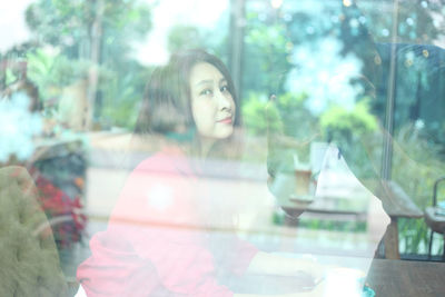 Young woman looking through glass window