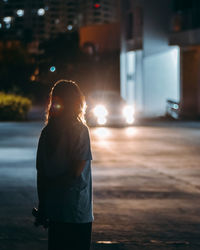 Girl standing on street at night