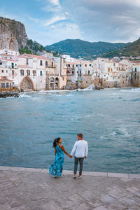 People standing on shore against cityscape