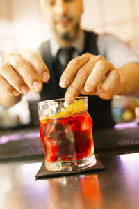 Bartender serving red drink in glass at counter