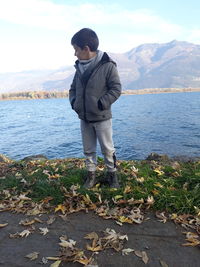 Young man standing by sea against mountains