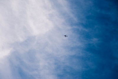 Low angle view of airplane flying against cloudy sky