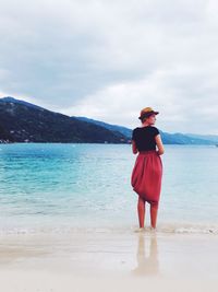 Rear view of man standing on beach against sky
