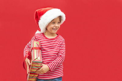 Portrait of cute girl wearing santa hat standing against yellow background