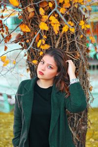 Portrait of young woman standing against plants