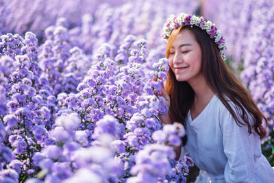 Smiling beautiful woman by purple flowering plants