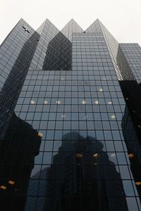 Low angle view of modern glass building against sky