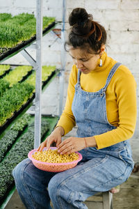 Woman choose seeds for planting new microgreens on the vertical indoor farm.  micro green trays