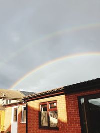 Low angle view of rainbow over building against sky
