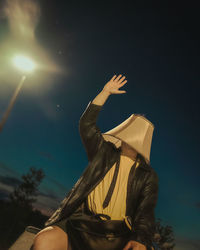 Man wearing a lampshade on his head raising an arm overhead