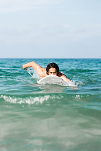 Man swimming in sea against sky