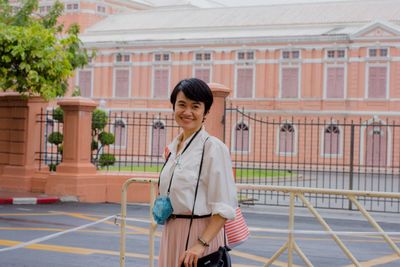 Portrait of a smiling woman standing against building