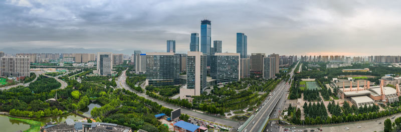 Panoramic view of buildings in city against cloudy sky