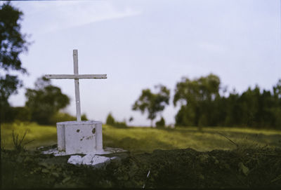 Close-up of cross on field against sky