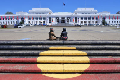 People sitting on road against sky in city