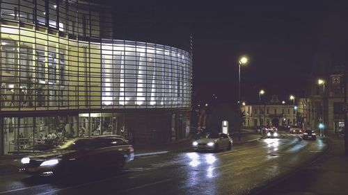 Illuminated street amidst buildings in city at night