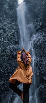 Low angle view of person wearing hat against waterfall