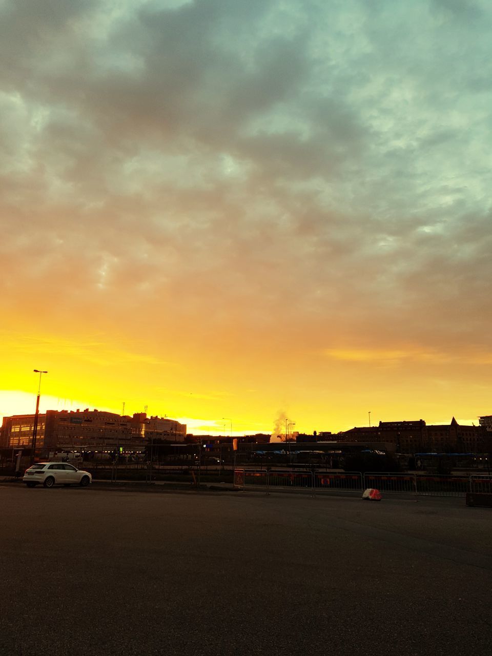 ROAD BY BUILDING AGAINST SKY DURING SUNSET