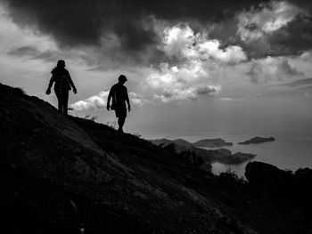 People on rock against sky